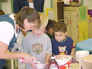 Trina Jimenez helps the children add their favorite toppings to their ice cream. Photo by Michelle Tyler