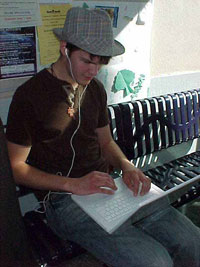 Photo of Palo Alto student listening to his iPod while working on his laptop.